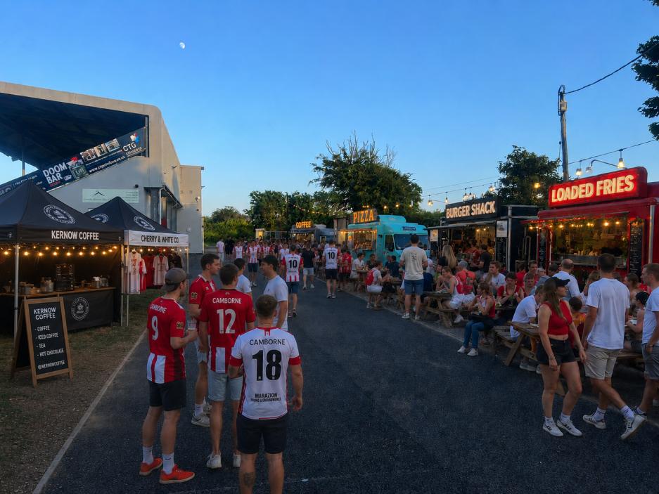 Food trucks and benches at the ground at dusk under string lights