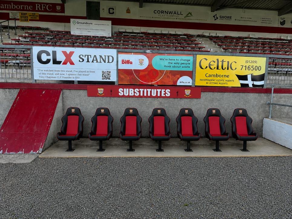 Branded stand signage behind the substitutes bench and sponsor boards