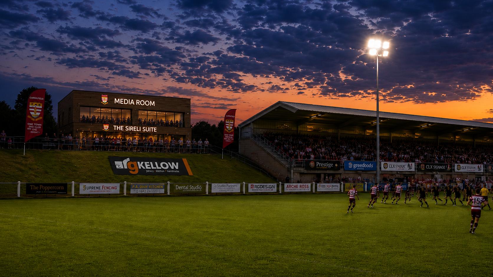 The Camborne RFC media room and stand under floodlights at sunset